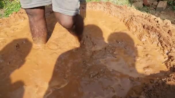労働者は粘土溶液を準備している この粘土は壁を作るためのモルタルとして使われる インドの農村地域では そのような土壌が多くの目的のために使用される 水のある赤い土 — ストック動画