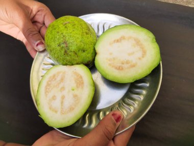  Slice guava on plate in black background. Its other names common guava, Psidium guajava, lemon guava, apple guava. This is is a small tree in the myrtlefamily. 