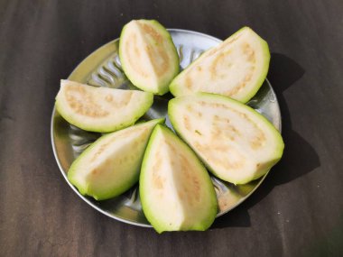  Slice guava on plate in black background. Its other names common guava, Psidium guajava, lemon guava, apple guava. This is is a small tree in the myrtlefamily. 