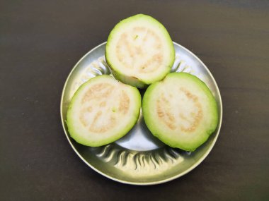  Slice guava on plate in black background. Its other names common guava, Psidium guajava, lemon guava, apple guava. This is is a small tree in the myrtlefamily. 