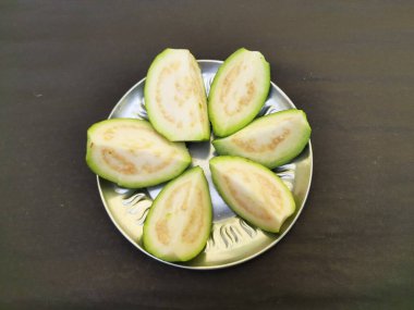  Slice guava on plate in black background. Its other names common guava, Psidium guajava, lemon guava, apple guava. This is is a small tree in the myrtlefamily. 