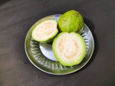  Slice guava on plate in black background. Its other names common guava, Psidium guajava, lemon guava, apple guava. This is is a small tree in the myrtlefamily. 