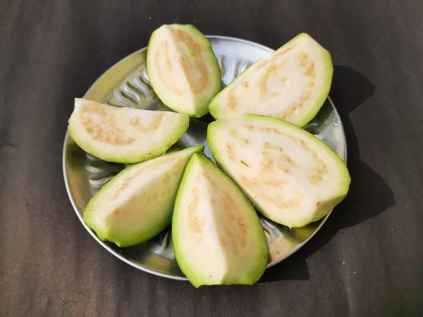  Slice guava on plate in black background. Its other names common guava, Psidium guajava, lemon guava, apple guava. This is is a small tree in the myrtlefamily. 