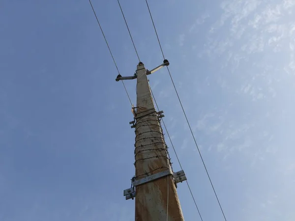 A electricity pole in blue sky background in rural area. Electricity cable on pole. Indian rural area electricity supply. Cement electric pole.