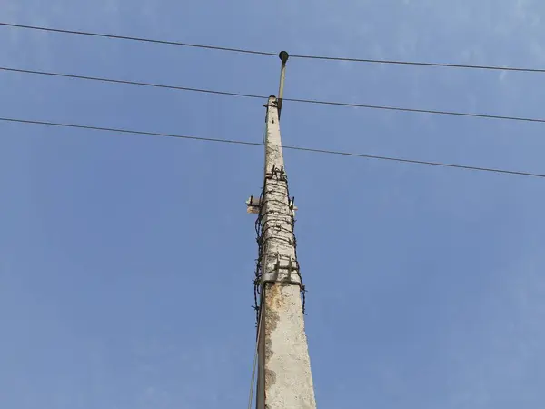 A electricity pole in blue sky background in rural area. Electricity cable on pole. Indian rural area electricity supply. Cement electric pole.