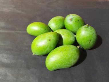 Siyah arka planda çiğ mango. Mango popüler bir meyvedir, ayrıca meyvelerin kralı olarak da bilinir. Turşusu çok lezzetli. Pişirilir ve sebzeye dönüştürülür. Siyah arkaplanda yeşil mango. 
