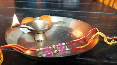 Puja plate decorated by a sister on the occasion of the festival of Raksha Bandhan.  Rakhi, lamp, and laddus are placed in a brass plate. A beautiful Pooja thali in India.