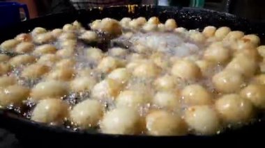 Gulab Jamun, an Indian sweet is being made in a sweet shop.  This sweet is being fried in hot oil.  It is then dipped in sugar syrup. A popular indian sweet. Traditional sweet of india. 