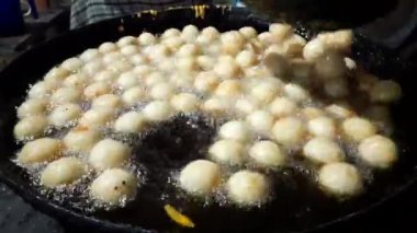 Gulab Jamun, an Indian sweet is being made in a sweet shop.  This sweet is being fried in hot oil.  It is then dipped in sugar syrup. A popular indian sweet. Traditional sweet of india. 