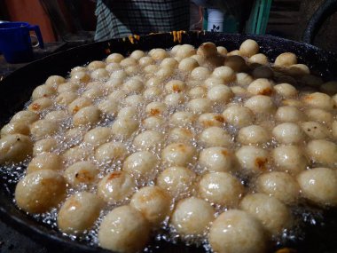 Gulab Jamun, an Indian sweet is being made in a sweet shop.  This sweet is being fried in hot oil.  It is then dipped in sugar syrup. A popular indian sweet. Traditional sweet of india. 