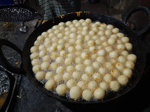 Gulab Jamun, an Indian sweet is being made in a sweet shop.  This sweet is being fried in hot oil.  It is then dipped in sugar syrup. A popular indian sweet. Traditional sweet of india. 