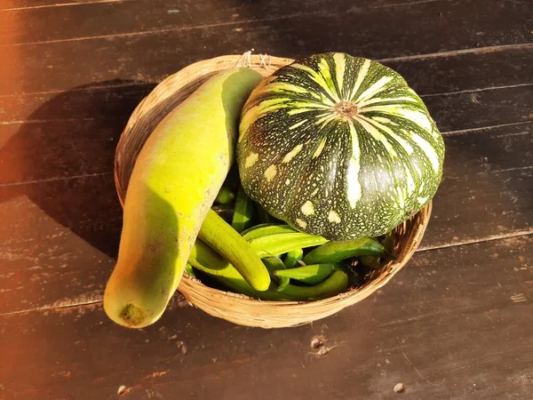 Bottle gourd, pumpkin, Sponge gourd and okra vegetable on Bamboo Basket. Many vegetables in basket. Vegetable in black wooden background.