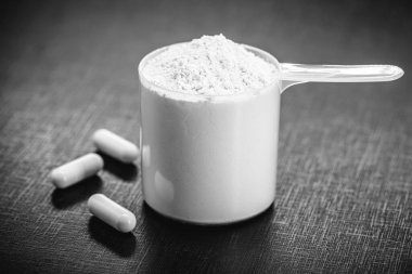 Amino acid supplement for sports use, creatine in a measuring spoon, hmb, bcaa, amino acid or powdered vitamin. sports nutrition concept