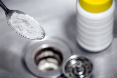 spoon with baking soda or sodium hydroxide powder, to unclog the kitchen sink drain