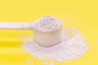 Kazein veya kafein tozlu kaşık ölçme, gıda takviyesi, sporcular tarafından kullanılan vitamin, sarı arka plan