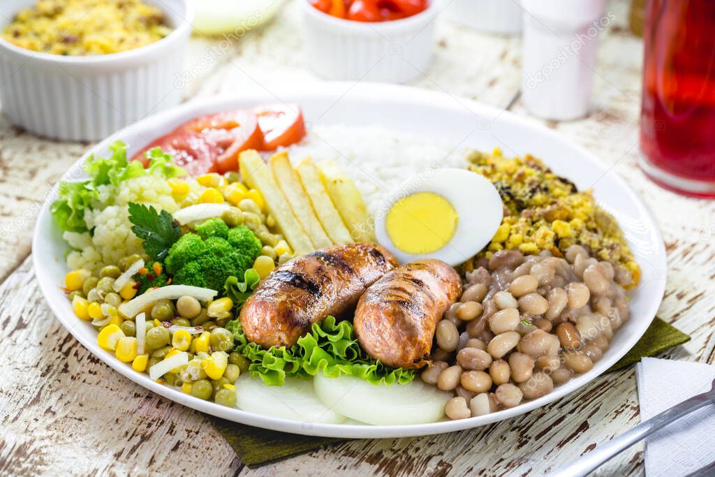 typical brazilian meal, rice and beans, tomato salad, boiled egg and french fries, called a traditional dish or executive dish