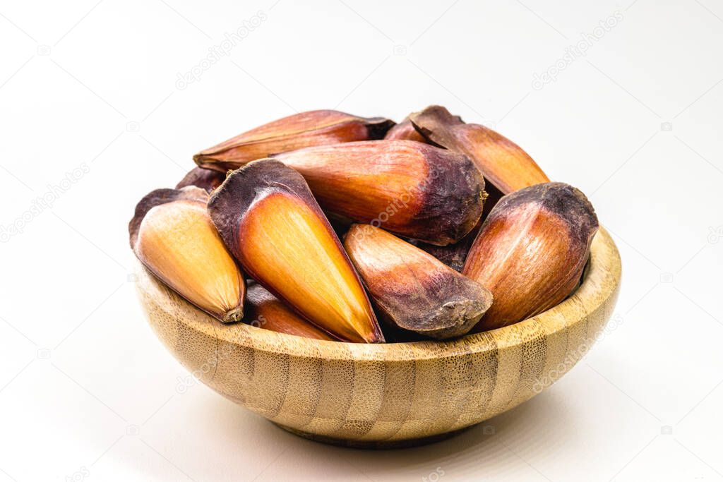 cooked pine nut seed in rustic wooden bowl, copyspace, isolated white background