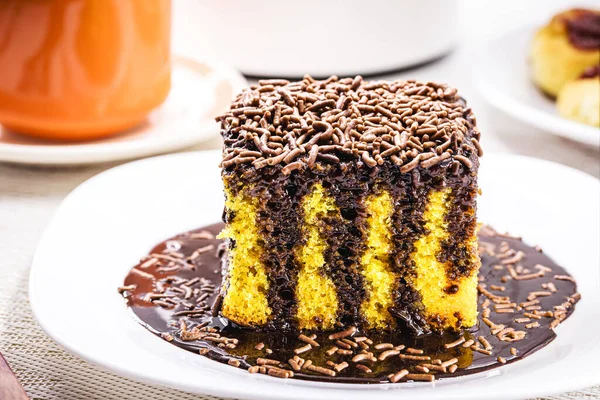 carrot cake with chocolate icing dripping on plate, served with latte and other sweets, bakery sweet, brazilian afternoon boat