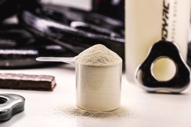 kaşık kreatin, whey veya kazein, whey takviyeleri, egzersiz protein barı, spor salonu arka planı, kas kütlesi kazancı
