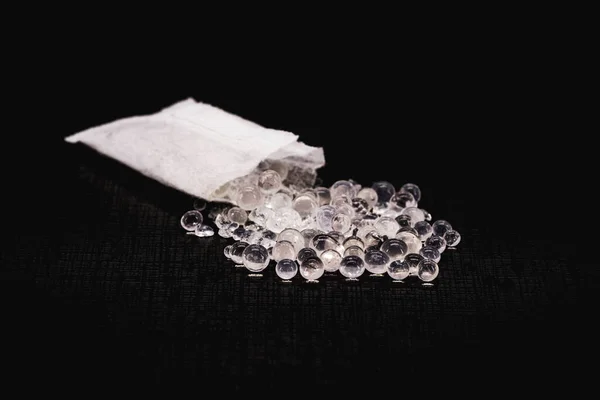 Desiccant or silica gel in white paper packaging and spread on isolated black background, anti mildew gel