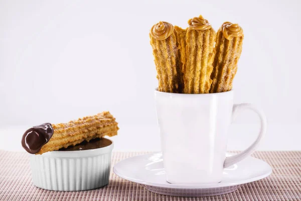 churros in a mug, traditional fried sweet from Latin America, Brazil, Colombia, United States and Portugal, served with or without filling, sprinkled with sugar, copy space