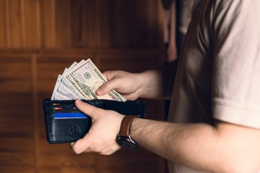 Bir adam içinde para ve kredi kartları olan bir cüzdan tutar.