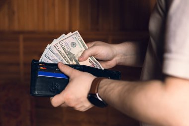 Bir adam içinde para ve kredi kartları olan bir cüzdan tutar.