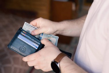 Bir adam içinde para ve kredi kartları olan bir cüzdan tutar.