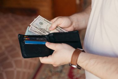 Bir adam içinde para ve kredi kartları olan bir cüzdan tutar.