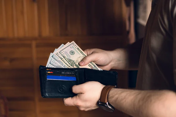 A man holds a wallet with money and credit cards