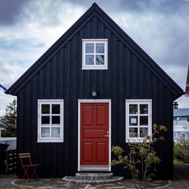 Hafnarfjordur, İzlanda - 17 Temmuz 2021: Siyah, geleneksel ahşap bir İzlanda evi. Bulutlu gökyüzü. Kimse yok.. 
