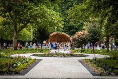 Busko Zdroj, Poland - July 31, 2021: People watching the traditional folk music concert in the spa park in Busko health resort. clipart