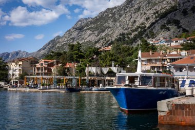 Kotor, Karadağ - 29 Nisan 2022: Eski Kotor kasabasında dar bir sokakta yürüyen iki genç kadın. Ortaçağ binalarının taş duvarları arasında asılı renkli bir çamaşır.. 