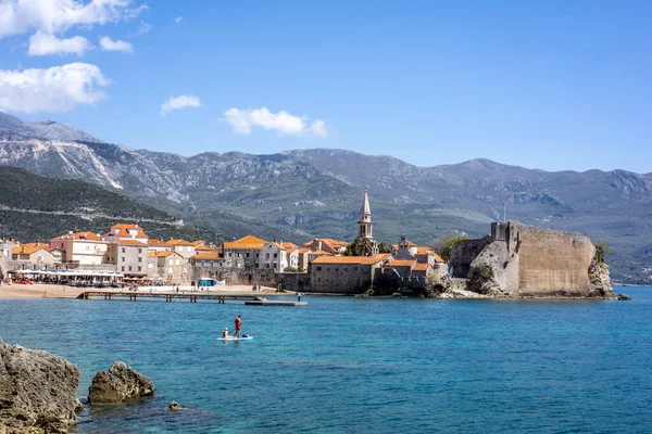 Budva, Karadağ - 28 Nisan 2022: Budva 'nın eski kenti ve Adriyatik kıyı şeridi. Ortaçağ kalesi binası, kumlu plaj, arka planda dağlar..