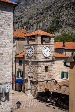 Kotor Montenegro - 29 Nisan 2022: Kotor eski kasabasındaki meydanda saat kulesi. Ortaçağ mimarisi, taş duvarlar ve turuncu kiremitli çatılar. 