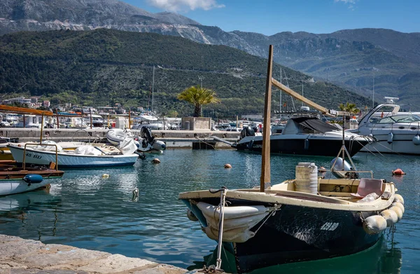 Budva, Karadağ - 28 Nisan 2022: Budva limanına demirlemiş küçük balıkçı teknesi. Güneşli bir gün, arka planda dağlar.