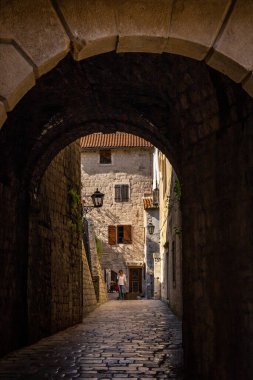 Kotor, Karadağ - 29 Nisan 2022: Kotor eski kasabasında dar bir geçitten geçen bir kadın.. 