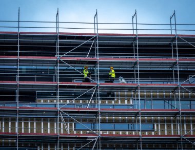 Reykjavik, Iceland - March 31, 2022: Building under construction in Reykjavik downtown. Workers in yellow vests on the scaffold. 