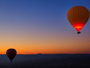 Sıcak hava balonları gündoğumu sırasında gökyüzünde. Valley adlı Cappadocia, Anadolu, Türkiye üzerinden uçan. Göreme Milli Parkı içinde volkanik dağlar.