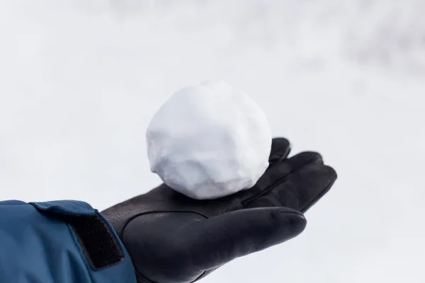 Boule de neige dans une main d'homme dans un gant — Photo