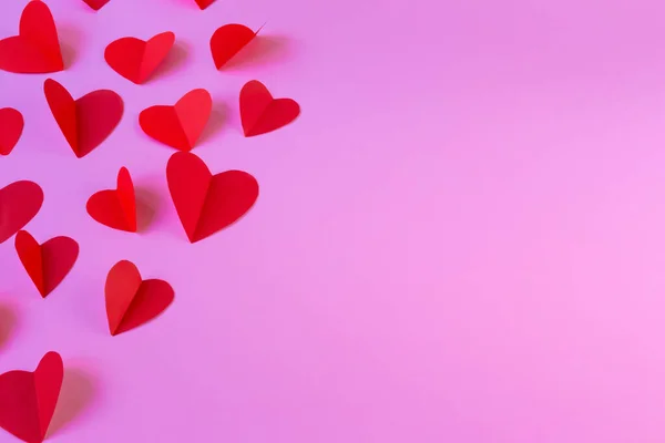 Pembe arka planda uçan kırmızı kalpler