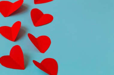 Soluk mavi arka planda kırmızı kalpler