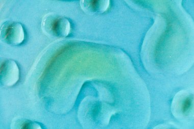 Mavi arka planda suyla kaplı sarı yağ lekeleri