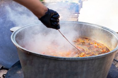 Bir şef dışarıda büyük bir fıçıda bograch çorbası pişirir. Yemek katı. Taze ve iştah açıcı.
