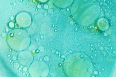 Yağ lekeleri, açık mavi arka planda suda daireler.