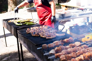 Şef ızgara sebze, sosis ve et hazırlar.