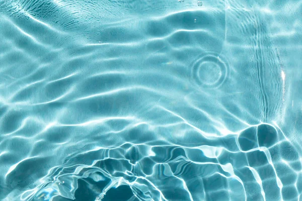 Water waves in the sunshine. Light blue textured background. Close-up, selective focus