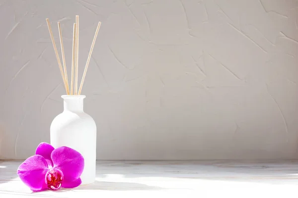 Ev için parfüm. Açık arkaplanda orkide çiçekli Aromatik sazlık ayırıcı. Barış, rahatlama ve zevk kavramı