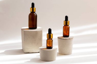 Beton podyumlarda pipeti olan kahverengi cam damlalar. Organik, doğal kozmetik. Güzellik, cilt bakımı. Spa ürünleri. Yaklaş, kopyalama alanı. Seçici odak