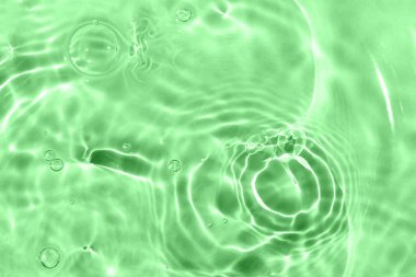 Güneş parlıyor, suyun üstünde kabarcıklar. Yeşil desenli arka plan. Yakın çekim, seçici odaklanma